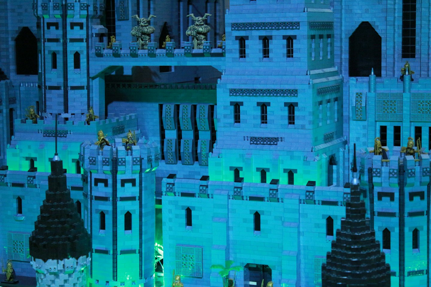 Skomplikowany model zamku z LEGO z wieżami i małymi złotymi figurkami.