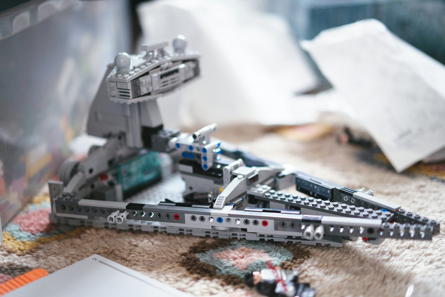 Szary model statku kosmicznego z klocków LEGO leży na wzorzystym dywanie.